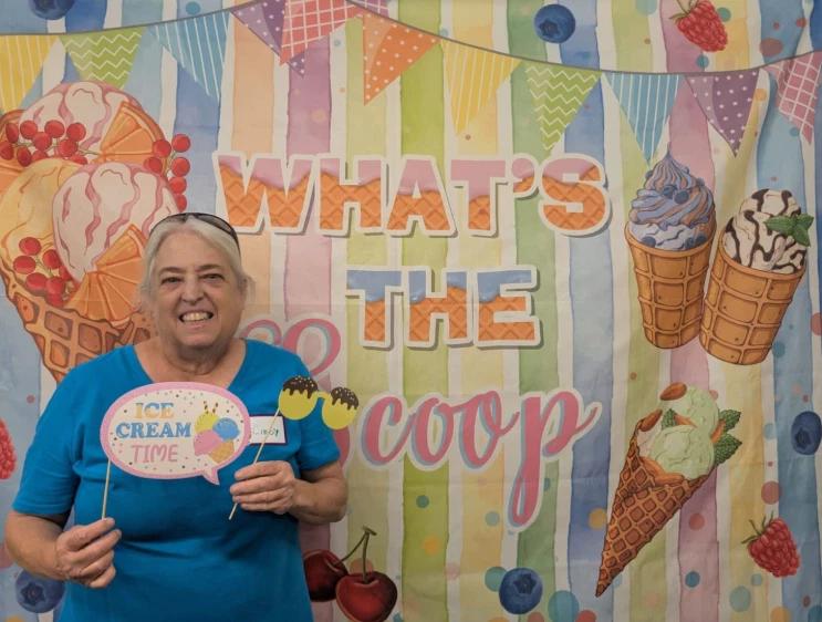 Resident smiling at the Sun City West Foundation Ice Cream Social photo booth with a What's the Scoop backdrop.