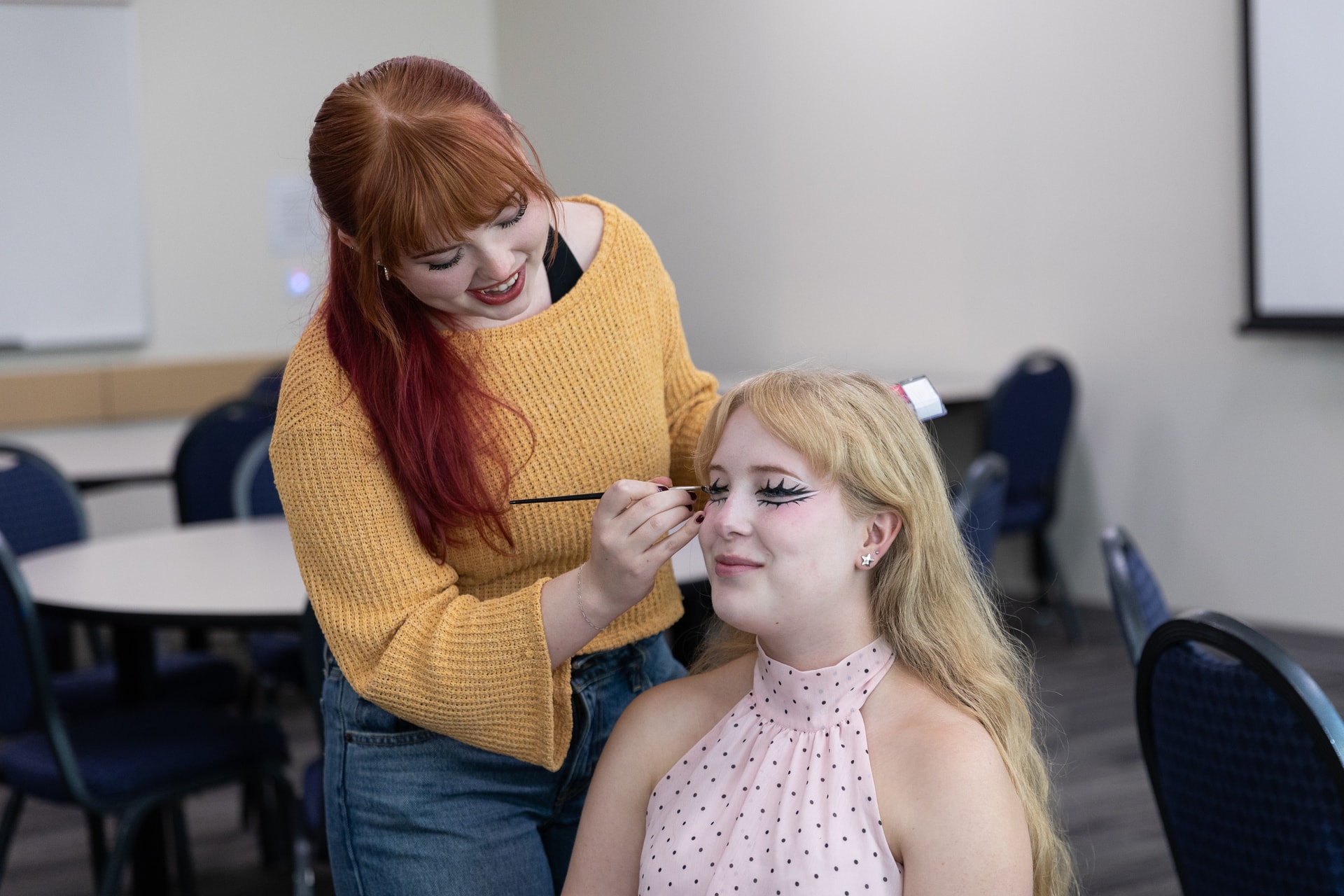 Makeup artist doing a drag makeover on a student
